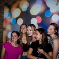 Group of grads smile at photo booth backdrop